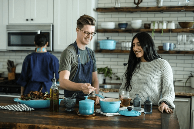 man and woman smiling while cooking