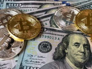 dollars spread out with bitcoins scattered on top