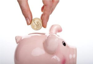 placing dollar coin in pink piggy bank