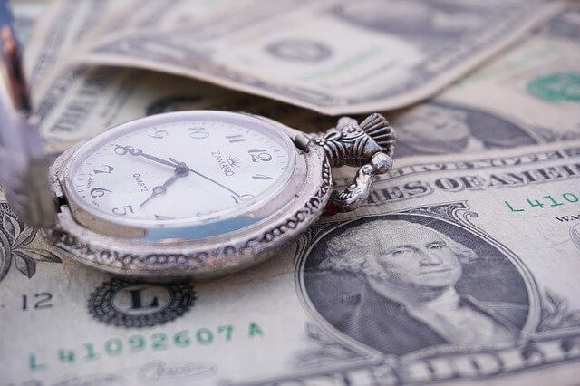 time piece laying on dollar bills